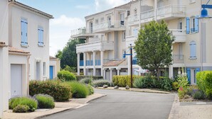 Una strada residenziale con edifici a più piani, balconi e giardini curati.