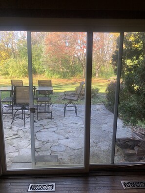 A patio with stone flooring and outdoor furniture, including chairs and a table.