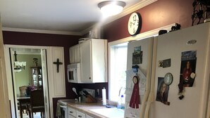 A kitchen with white cabinets, a refrigerator, a microwave, and a clock on the wall. - EAA house on golf course (Oshkosh)