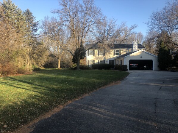 A two-story house with a garage, surrounded by trees and a well-maintained lawn.