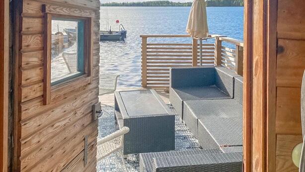 En stuga byggd av trä med utsikt över en lugn sjö och en brygga.