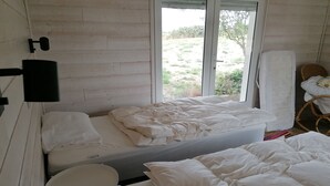 Una habitación con una cama, una mesita redonda y una ventana que da a vistas de follaje.