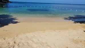 A beach with clear water, a sandy shore, and a boat in the distance. - Family friendly Townhouse by the Bay , private Beach & Pool , Negril  (Negril)