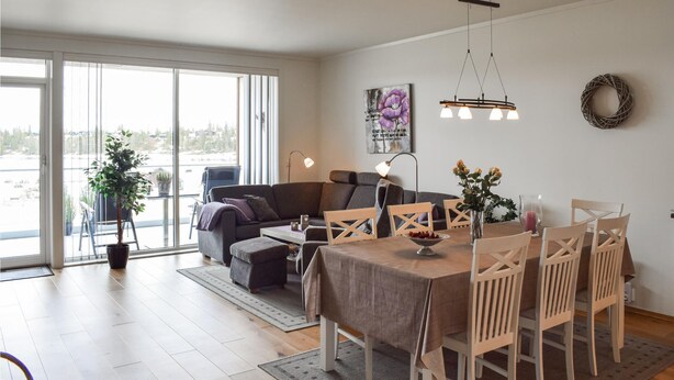 Una sala de estar moderna con comedor, ventanas amplias y vistas al exterior.