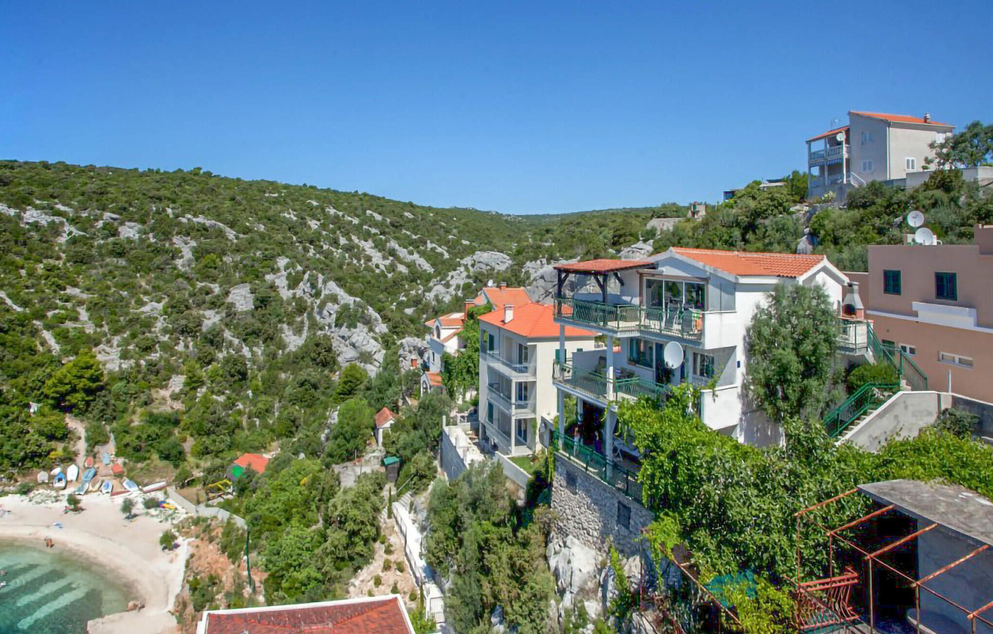 Zona residencial costera con casas modernas, una playa y un paisaje montañoso.