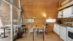 A modern kitchen with wooden walls, a dining area with white chairs, and a large window.