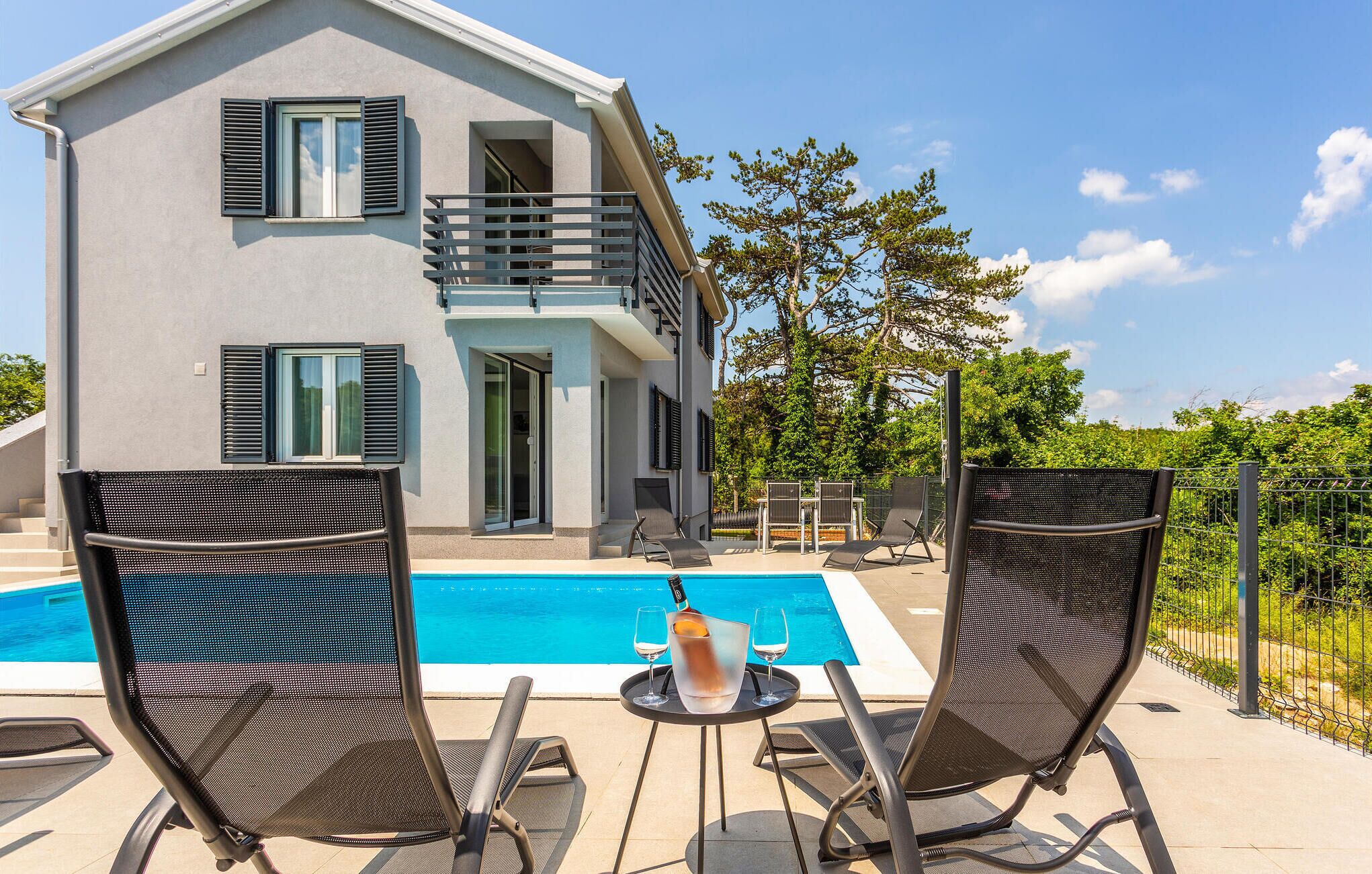 Ein zweigeschossiges Haus mit Balkon, Swimmingpool und Sitzgelegenheit im Freien.