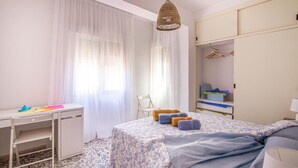 Un dormitorio con cama, escritorio, silla, armario y una lámpara colgante.
