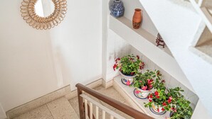 Una escalera con barandilla blanca, plantas en macetas y adornos en la pared.