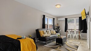 Un salon moderne comprenant un canapé, une table basse et un coin repas avec des chaises.