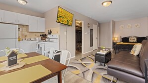 Un espace de vie compact comprenant une kitchenette, un coin repas et une chambre.