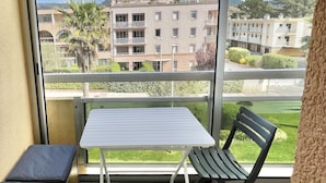 Un balcón con una mesa y dos sillas, con vistas a un complejo de edificios y un paisaje verde.