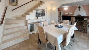 A dining area with a table set for four, a staircase, a kitchen area, and a fireplace. - Beach front home in Splitska with house sea view (Splitska)