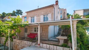 A two-story house with a balcony, a red chair, and a stone staircase leading to the upper floor. - Beach front home in Splitska with house sea view (Splitska)