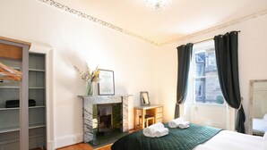 A bedroom with a bed, a fireplace, a wardrobe, and a window with curtains. - A fabulous 2-bedroom apartment in the heart of Edinburgh (Edinburgh)