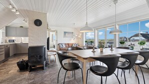 A modern kitchen with a built-in stove, dining area with a large table and chairs, and a view of the countryside through large windows. - Beautiful home in Ringkøbing with sauna (Ringkøbing)