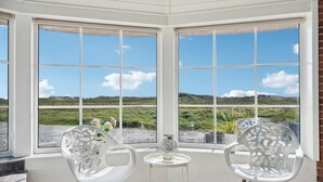 A corner room with large windows, two white chairs, a small table, and a decorative vase. - Beautiful home in Ringkøbing with sauna (Ringkøbing)