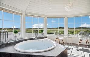 Un baño moderno con una bañera grande, ventanas amplias y vistas al campo.