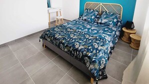 Un dormitorio con una cama, un espejo redondo, un taburete pequeño y una lámpara colgante.