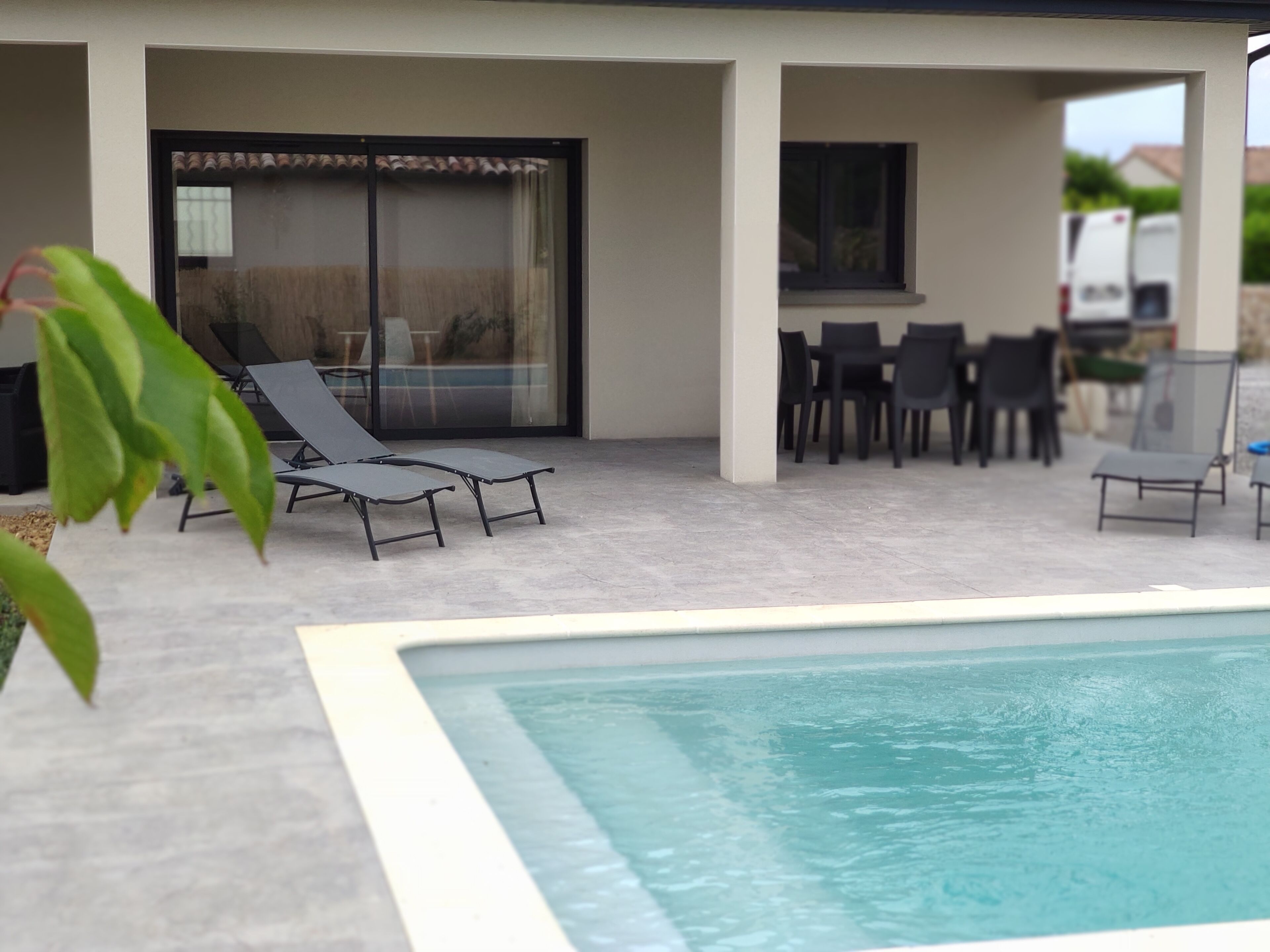 A pool area with lounge chairs and a dining set.