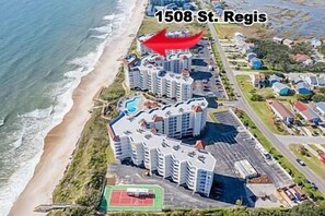 An aerial view of a coastal residential area with high-rise buildings, a beach, and a tennis court. - 3BR Oceanfront Condo in NTB with Elevator & Community Pool (North Topsail Beach)