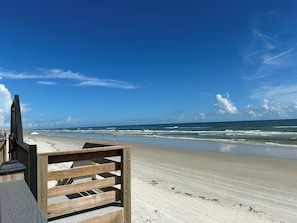 A beach with a wooden structure, likely a beach chair or part of a boardwalk, and the ocean in the background. - Sunrise View over the ocean! Direct oceanfront complex in New Smyrna! (New Smyrna Beach)