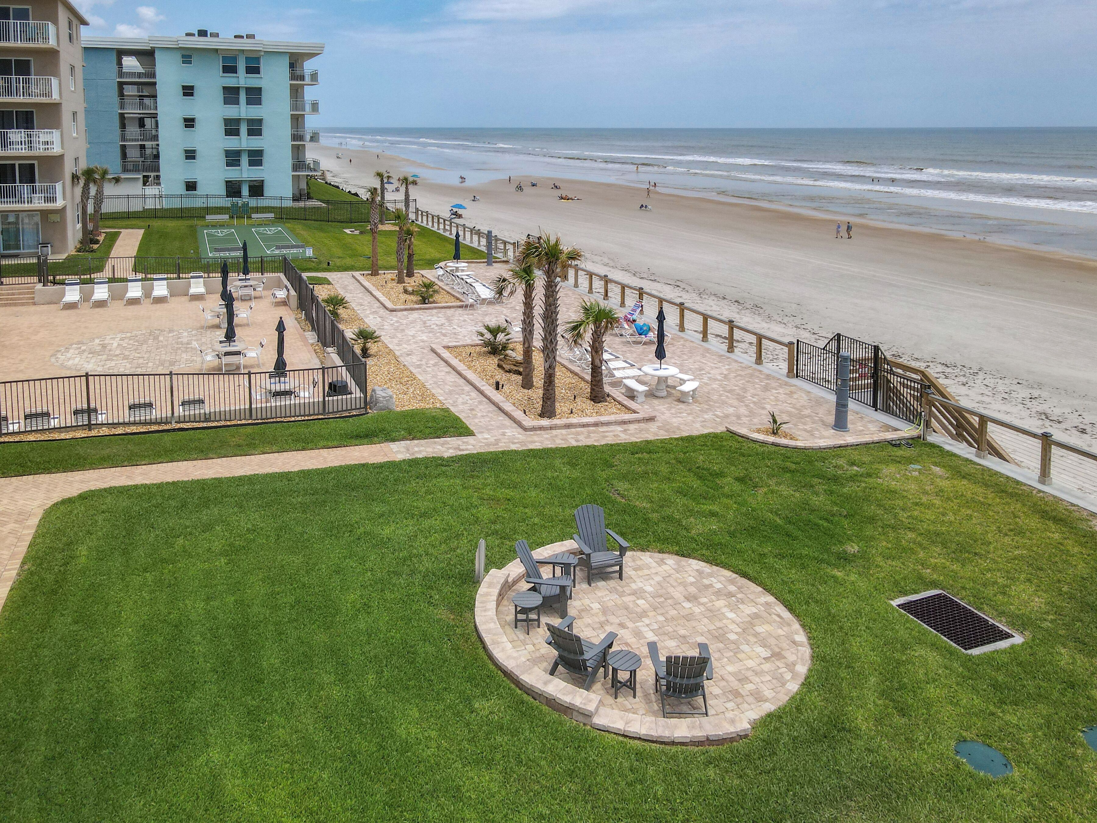 A beachfront hotel with a patio area featuring outdoor seating and a view of the beach.