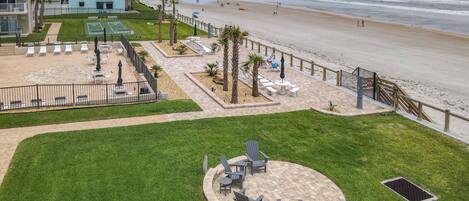 A beachfront hotel with a patio area featuring outdoor seating and a view of the beach.