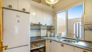 A compact kitchen with white cabinets, a built-in oven, a sink, and a window providing natural light. - Gorgeous apartment in San Javier (San Javier)