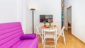 A room with a purple sofa, a small table with chairs, a TV, and a floor lamp. - Gorgeous apartment in San Javier (San Javier)