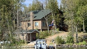 Eine Holzhütte an einem See mit einer Anlegestelle, umgeben von Bäumen.