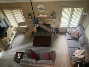 A living room with a fireplace, a ceiling fan, a sofa, a coffee table, and a TV.