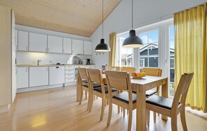 A modern kitchen with white cabinets, a wooden dining table with chairs, and pendant lights. - Beautiful home in Gråsten with kitchen (Gråsten)