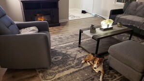 A cozy living room with a fireplace, a coffee table, and a dog resting on a rug. - Comfortable 3 Bedroom, 3 Bathroom With Amenities! (Savannah)