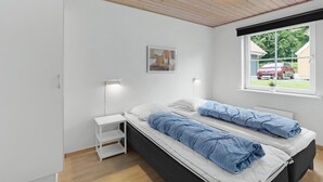 A bedroom with a bed, a bedside table, a lamp, a window with a view of a car and greenery outside. - Nice home in Gråsten with WiFi (Gråsten)