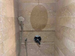 Een bad/douchecombinatie, handdoeken, zeep, toiletpapier