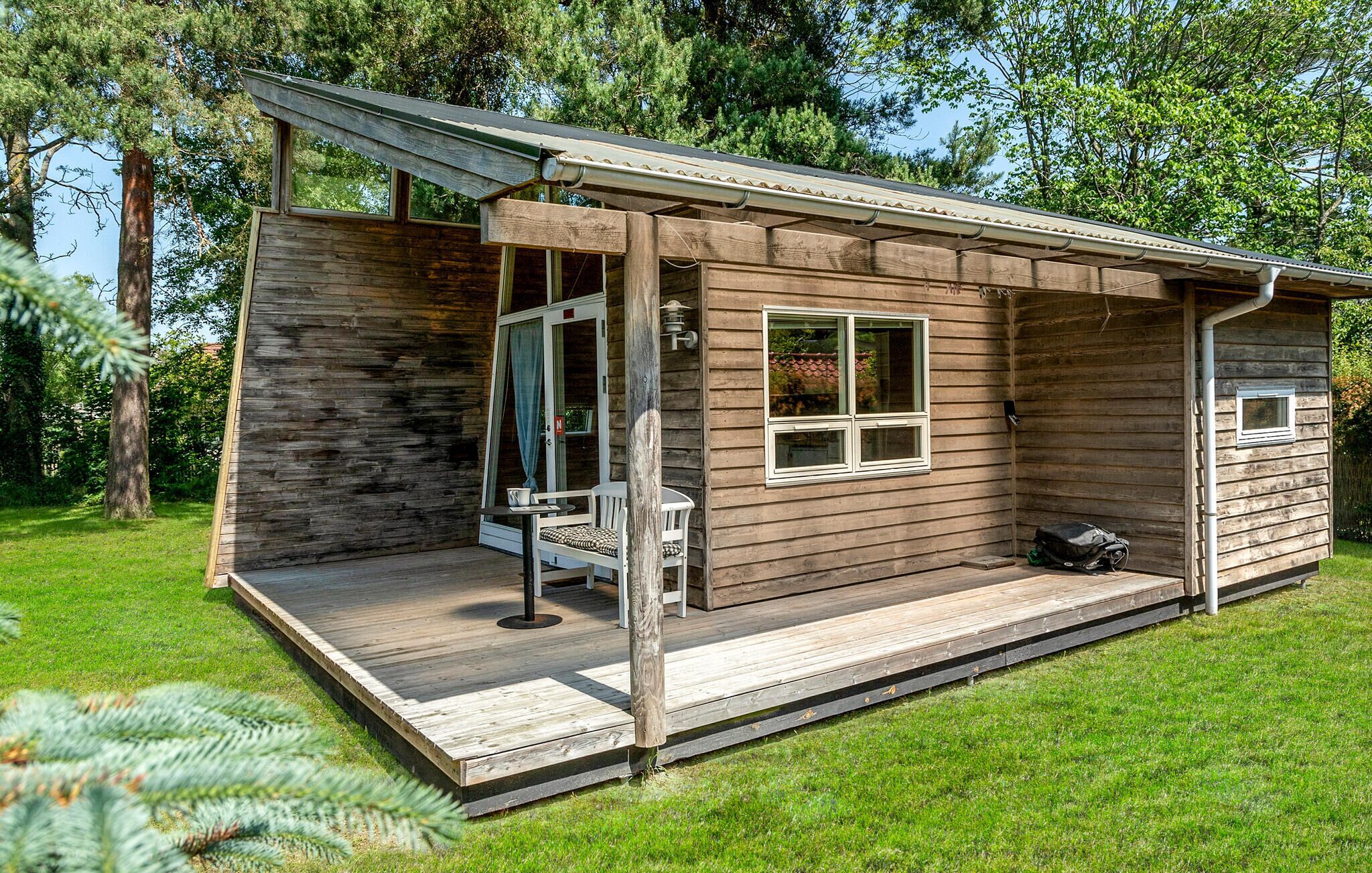 Ein kleines Holzhaus mit Veranda, einem Fenster und einer Tür.