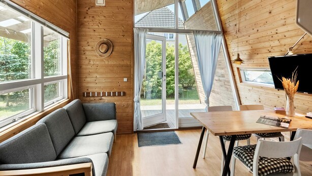 L’intérieur d’un chalet accueillant, avec un canapé, une table à manger et des chaises.