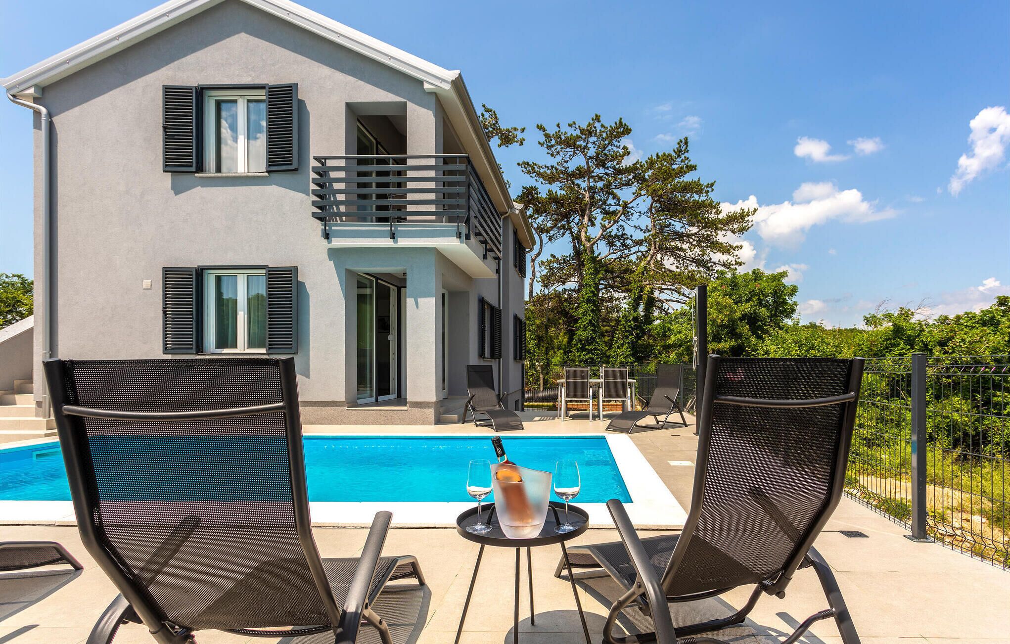 Ein modernes, zweistöckiges Haus mit Pool, Außenbereich und Balkon.