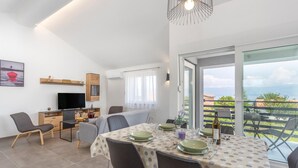A modern dining area with a table set for four, a television, and a view of the outdoors. - 2 bedroom nice apartment in Vrbnik (Vrbnik)