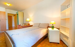 A hotel room with a bed, two bedside lamps, a wardrobe, a sofa, and a small table. - Beautiful apartment in Portoroz (Portoroz)
