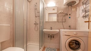 Une salle de bain équipée de toilettes, d’une douche, d’un lavabo et d’un lave-linge.