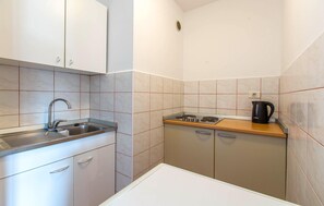 Prepare meals in this kitchen with a gas stove, stainless steel sink, and kettle.