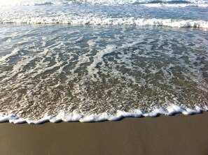 A sandy beach with gentle waves lapping at the shore.