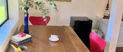 A dining table with a vase of green plants, books, and a cup.