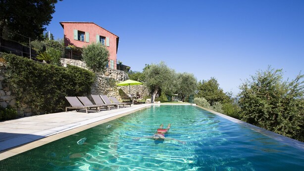 Ein Schwimmbecken mit klarem Wasser, umgeben von Liegestühlen und einer Steinmauer.