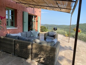 Relax in a serene outdoor space with a sofa, armchairs, and a table, sheltered by a thatched roof.