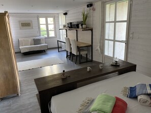 Relax in this stylish room featuring a large bed, sofa, and dining area.
