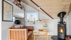 Een gezellige woonkamer met een houten bank, een eettafel, een open haard en een kaart aan de muur.