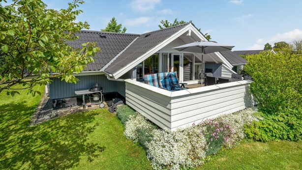 Een huis met een overdekte patio, een barbecue en een tuin.